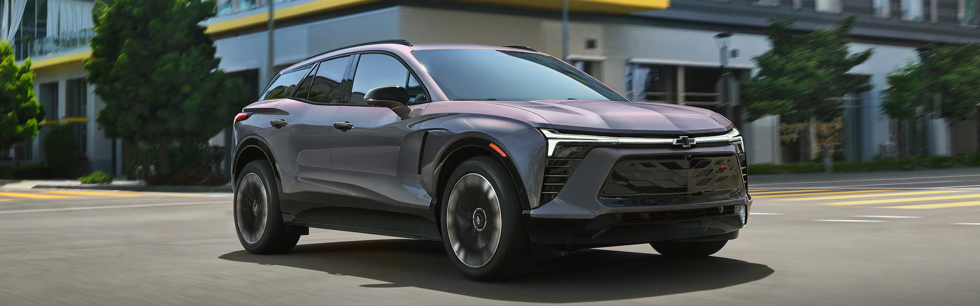 2026 Chevrolet Blazer EV driving on a city street, showcasing its sleek design and modern features.